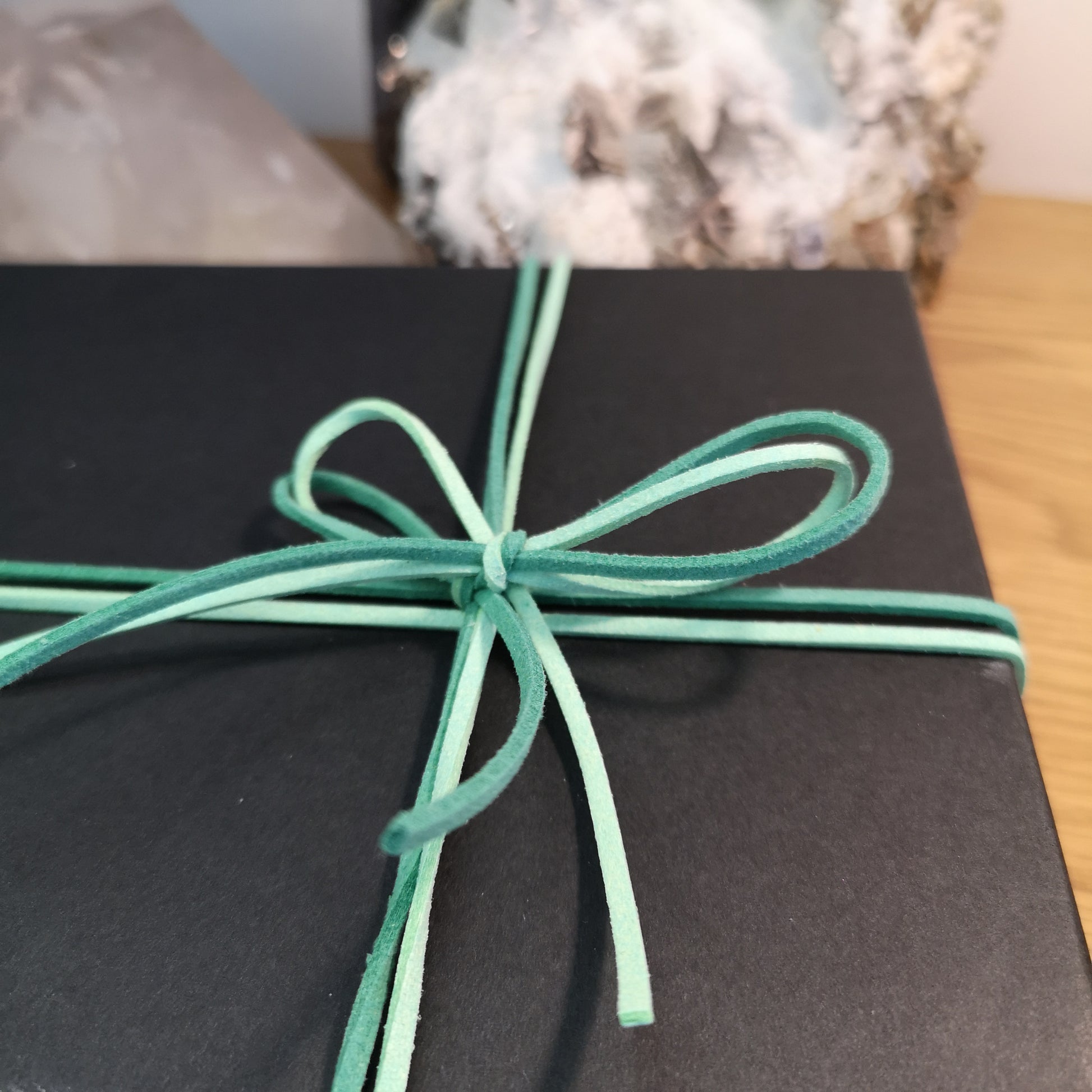 Green ribbon tied on a black box with a blurred background