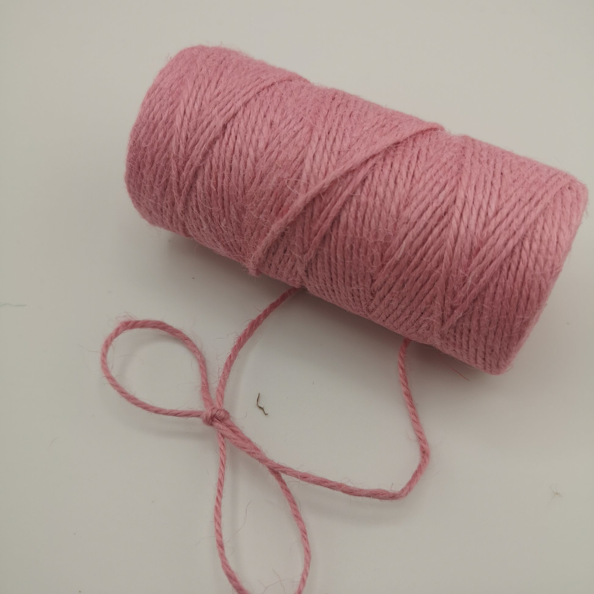 Pink jute twine roll on a white background