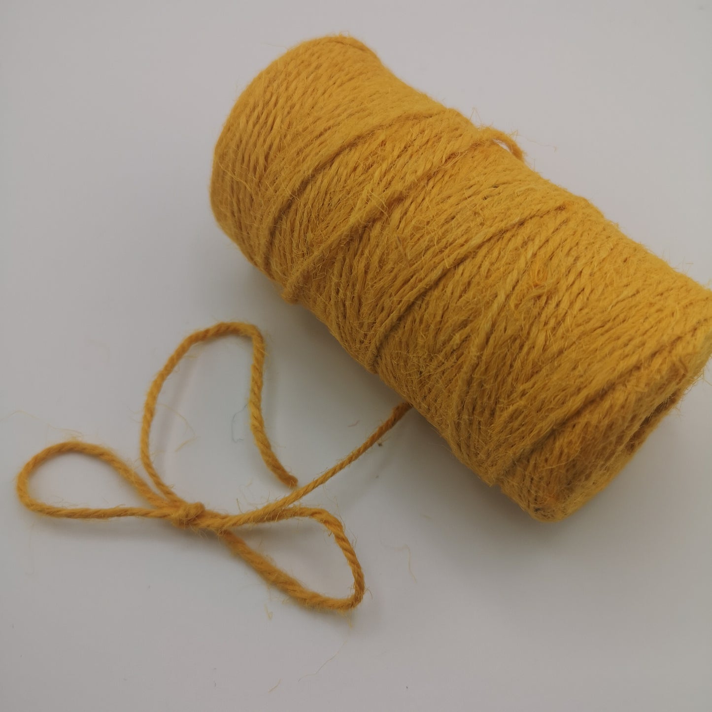 Yellow jute twine spool on a white background for crafting, gift wrapping