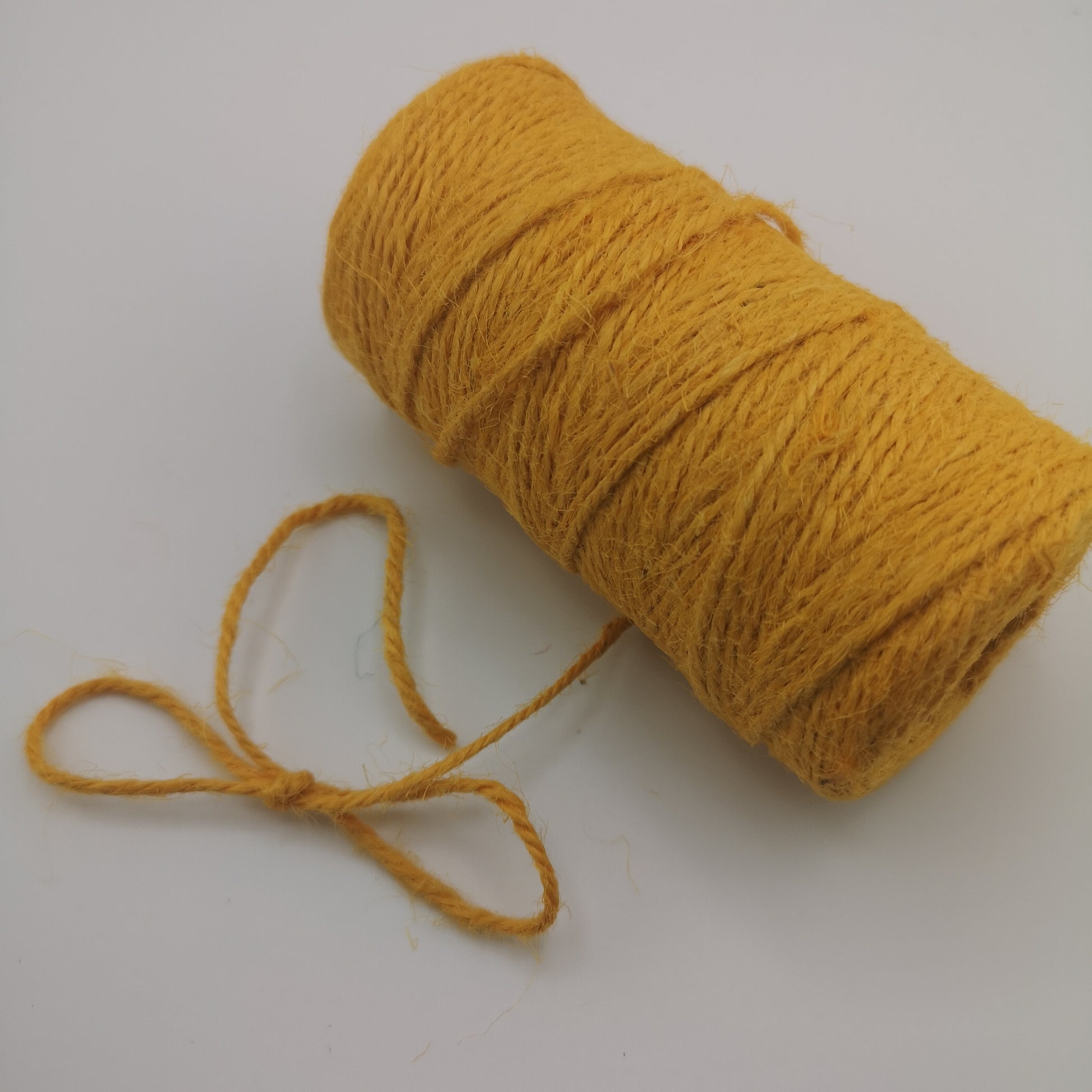 Yellow jute twine spool on a white background for crafting, gift wrapping