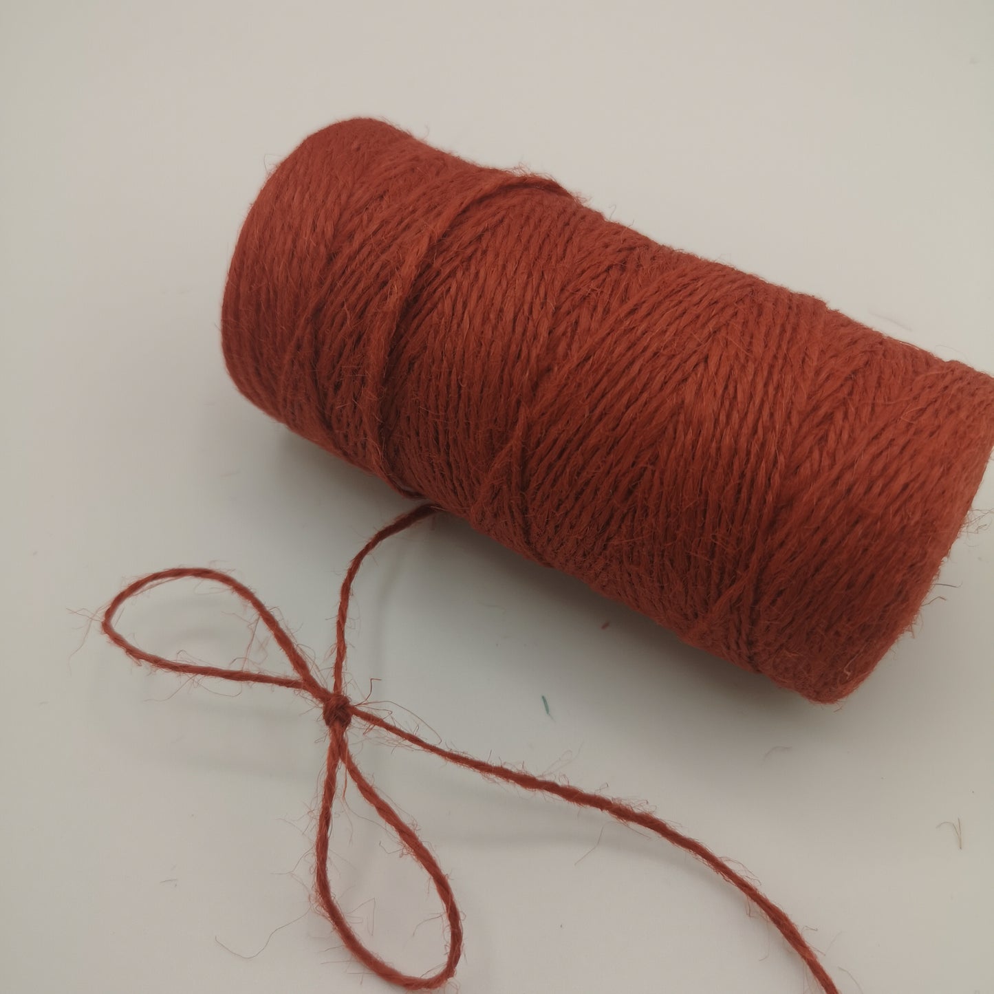 Spool of red jute twine on a white background