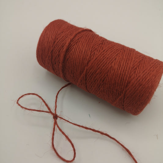 Spool of red jute twine on a white background